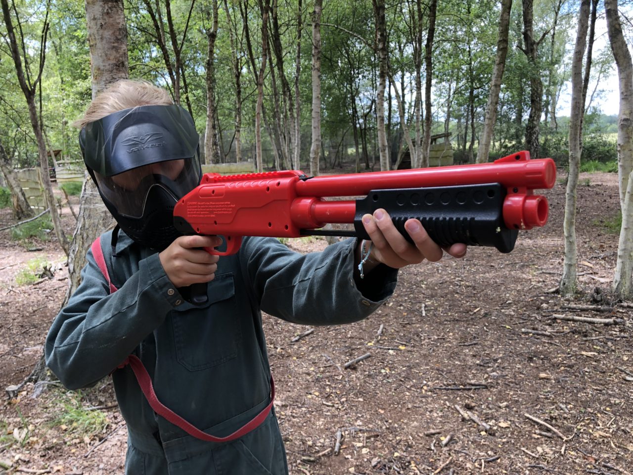 Kind staat in paintballbos en richt nauwkeurig met kinderpaintball gun